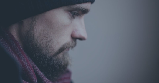 Profile of a young man with beard with a sad expression.