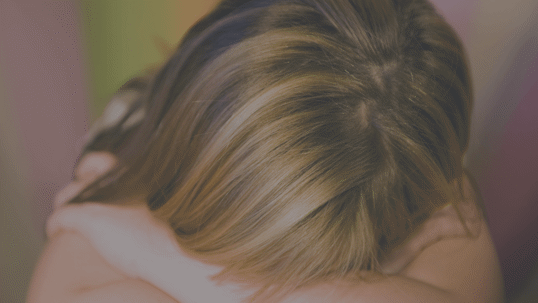 image of young child with head down on top of folded arms.