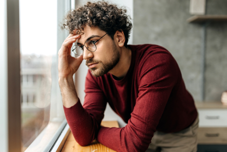 Man looking out a window trying not to blame himself for the childhood sexual abuse he received.